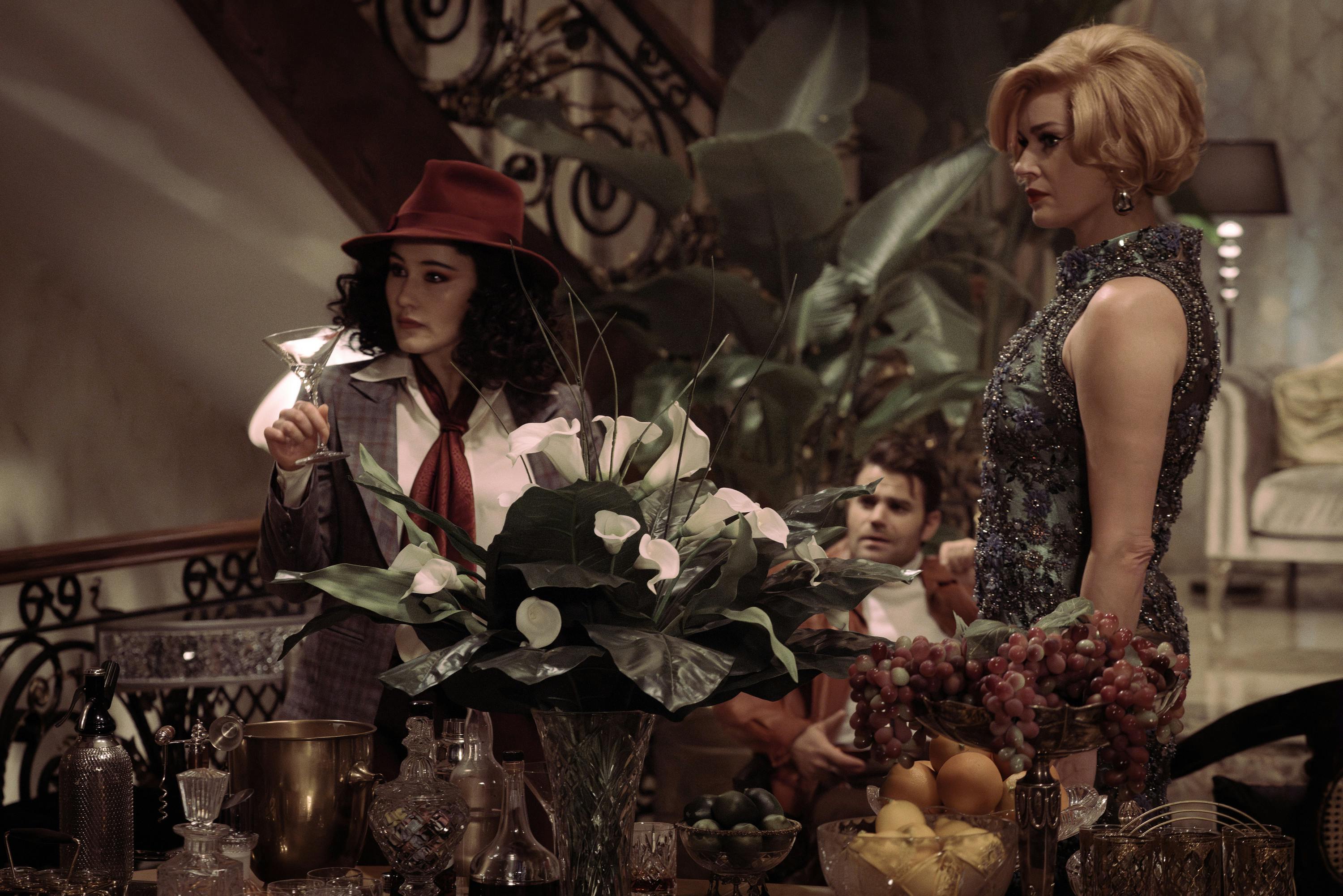 In the Holodeck, La'An as Amelia Moon lifts a martini glass for inspection in front of Sunny Lupino and Maxwell Saint in 'A Space Adventure Hour'