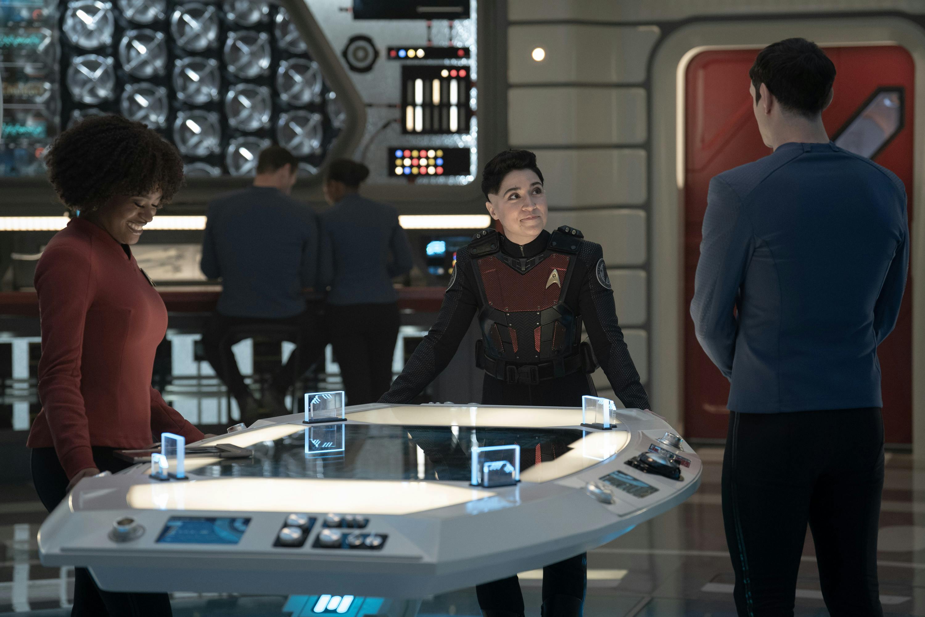 Ortegas, in her flight suit, debriefs with Uhura and Spock in the Science Lab in 'Terrarium'