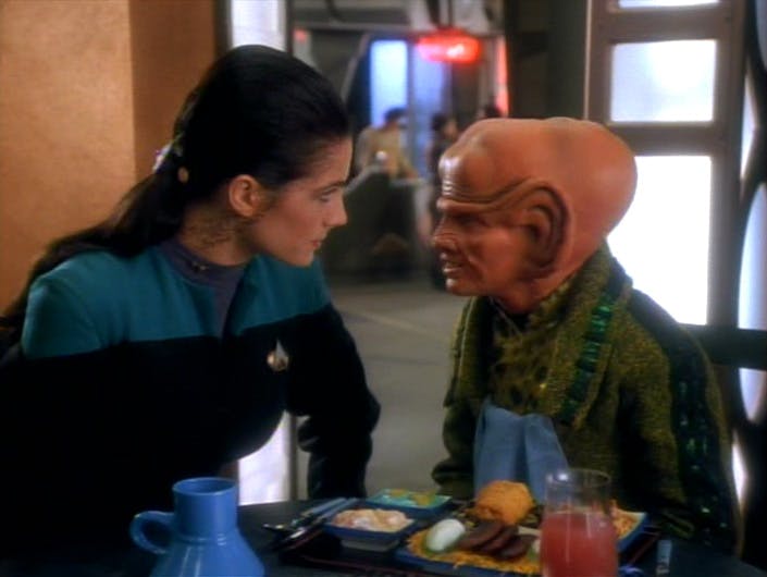Sitting at the replimat, Jadzia Dax and Pel look at each other face to face in 'Rules of Acquisition'