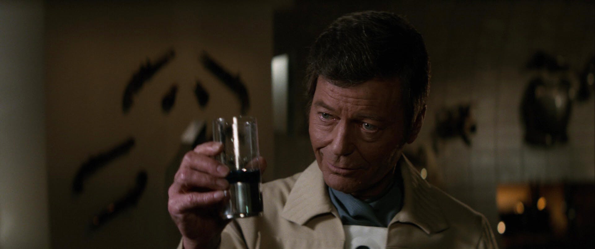 McCoy raises a glass of blue Romulan whiskey and nods at Kirk in Star Trek II: The Wrath of Khan 