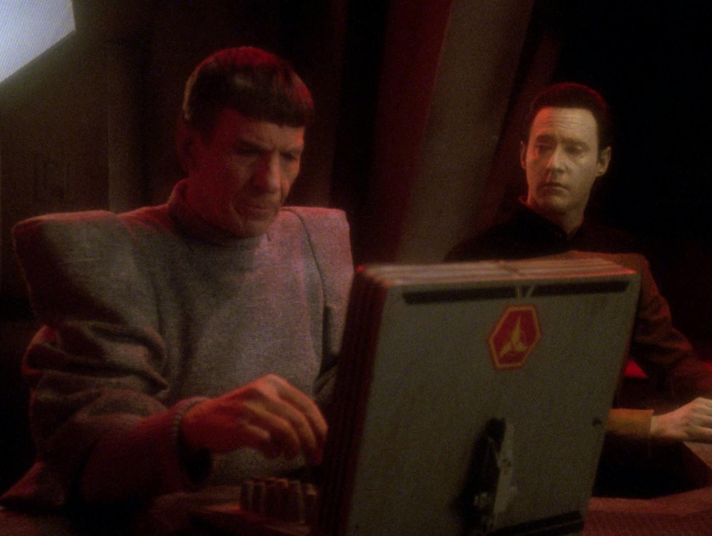 Spock types at a Klingon station as Data looks over his shoulder towards the admiral in 'Unification II'