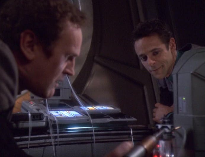 Julian Bashir looks over and smiles while Miles O'Brien tinkers around in 'Extreme Measures'