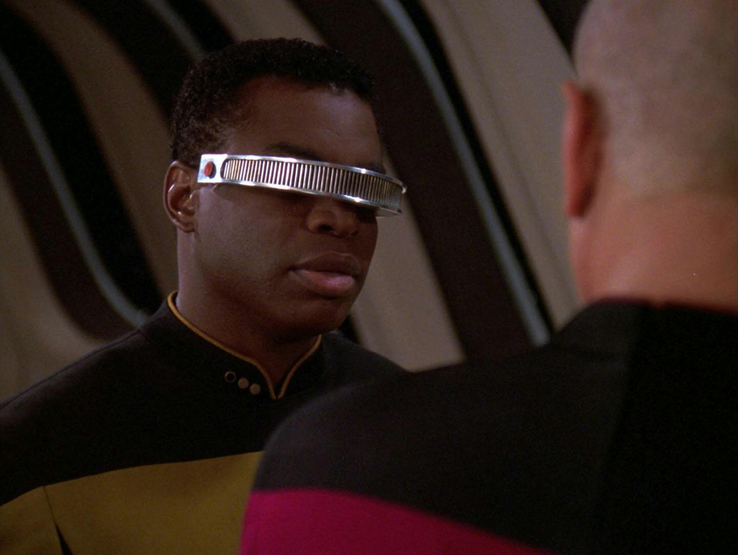 In the observation lounge, Geordi La Forge approaches Captain Picard by a window in 'Force of Nature'