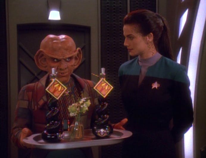 Quark carries a tray with two bottles of Kanar as gifts for Cardassian scientist guests as Jadzia Dax looks over at him questioning his angle in 'Destiny'