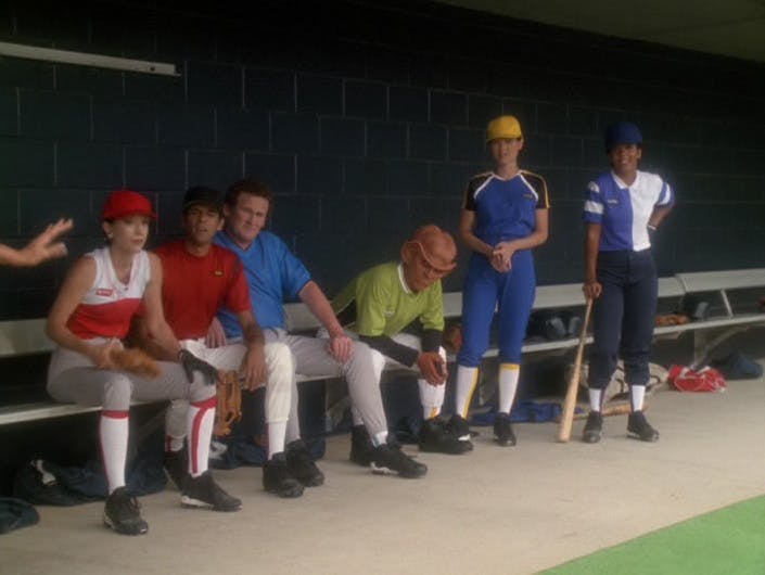 The DS9 crew in civilian baseball gear sit in the dug out and look out into the field in 'Take Me Out to the Holosuite'