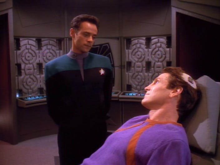 In Sickbay aboard Deep Space 9, Dr. Julian Bashir looks over the laying down Vedek Bareil with his scalp exposing his brain in 'Life Support'