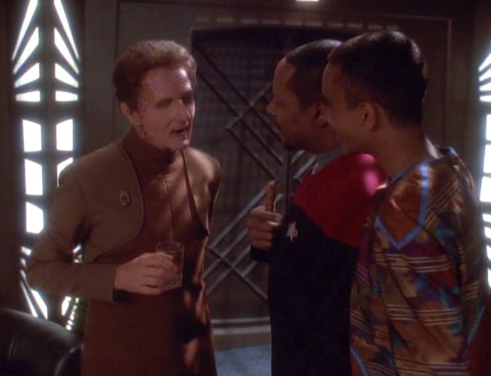 Curzon Dax in the body of Odo, with a glass in his hand, converses with Ben and Jake Sisko in 'Facets'