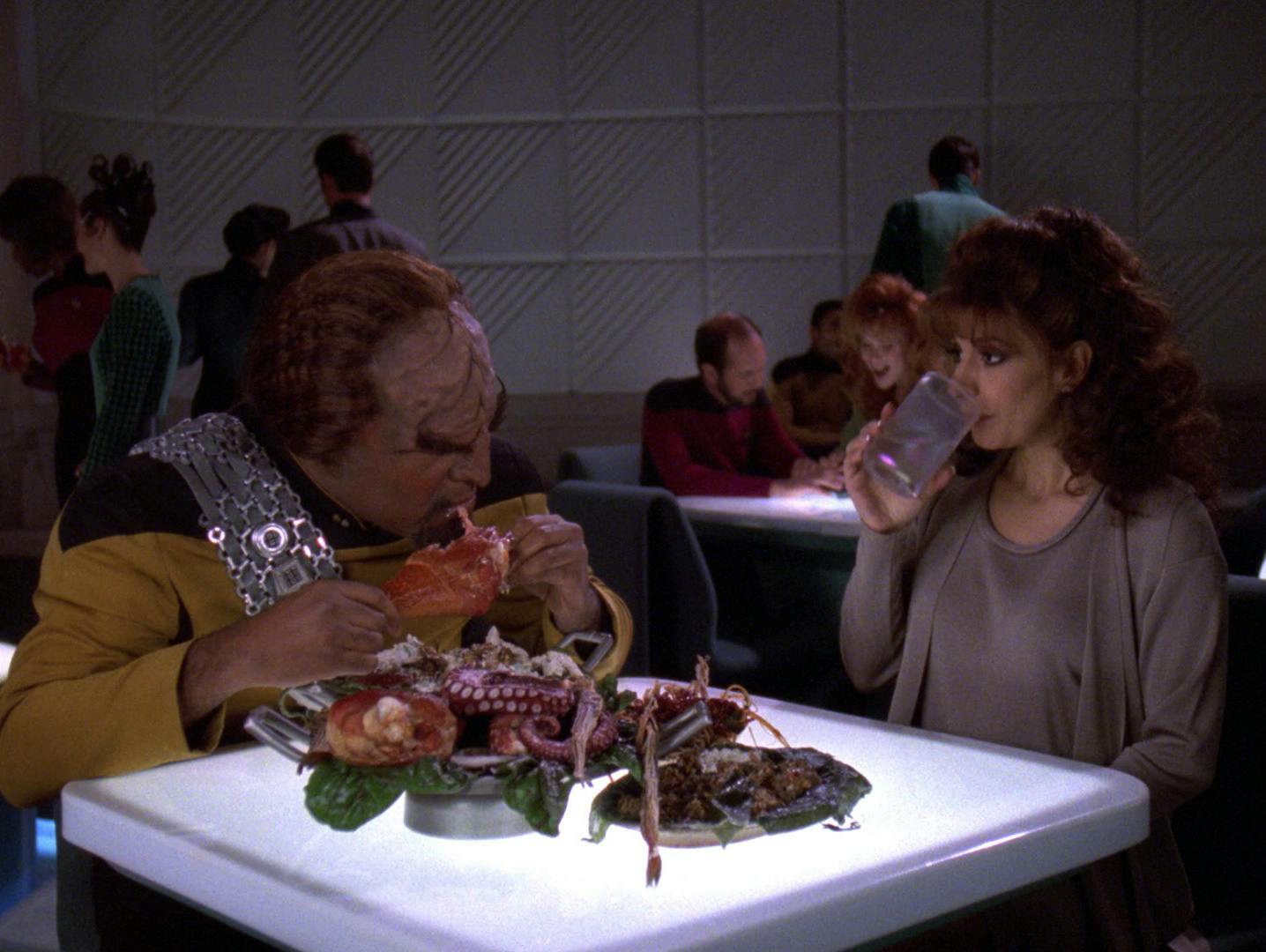 At 10 Forward, Worf feasts on a number of different delicacies while Deanna Troi drinks up her water in 'Genesis'