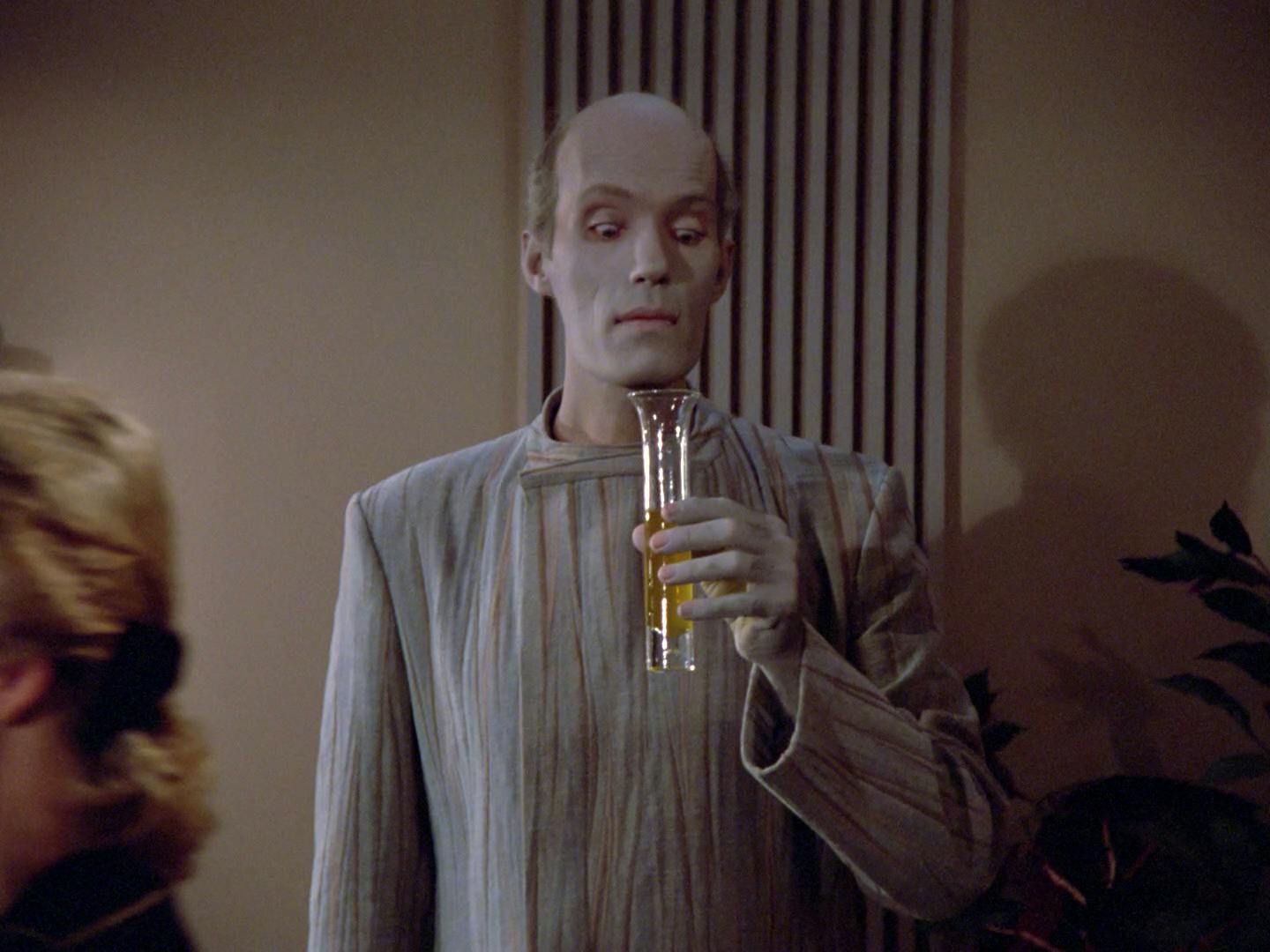 At an engagement dinner, Mr. Homn looks down at his cocktail glass with a surprised wide eye look in 'Haven'