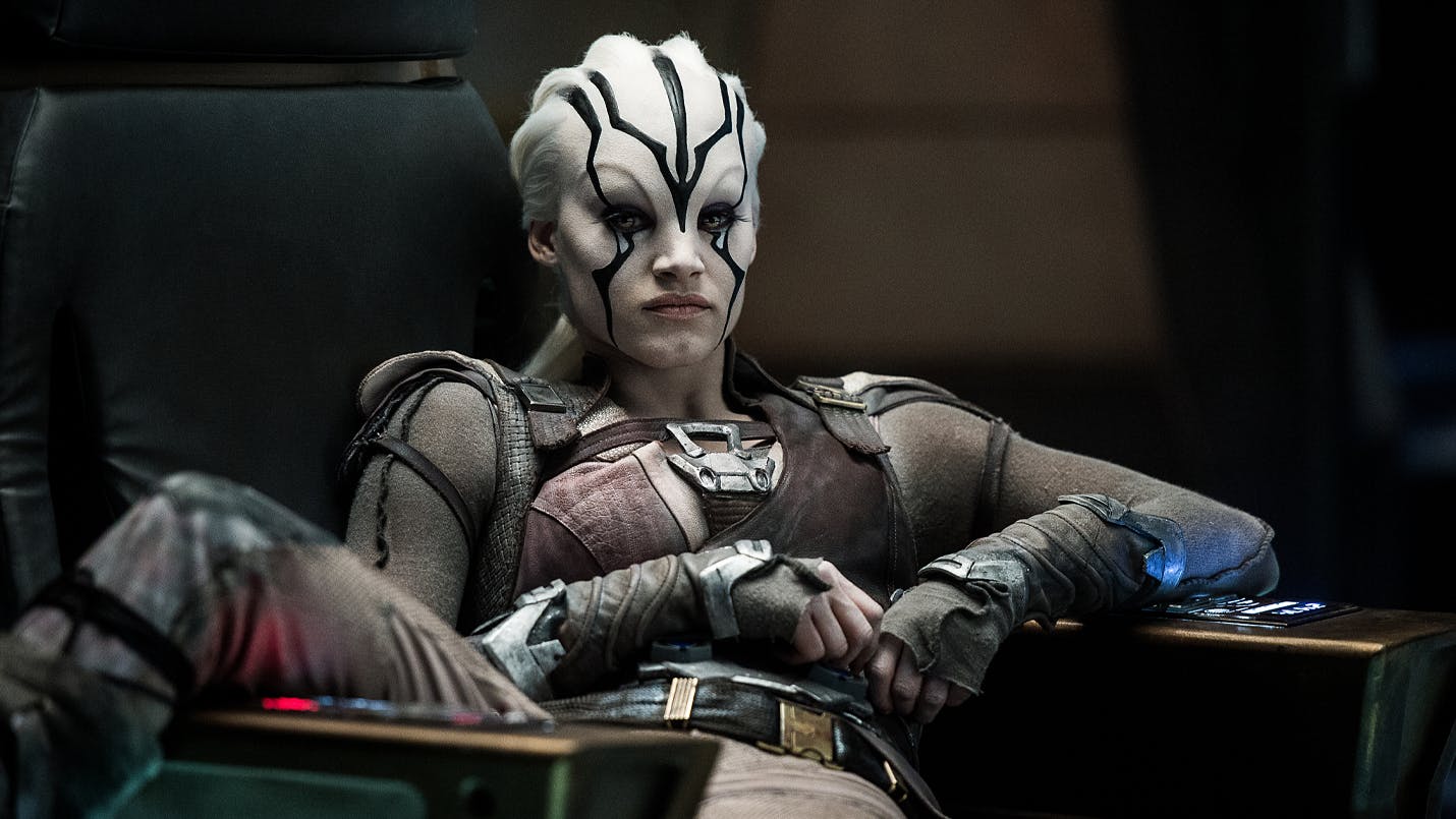 Jaylah sits sprawled in the captain's chair with her leg over the arm in Star Trek Beyond