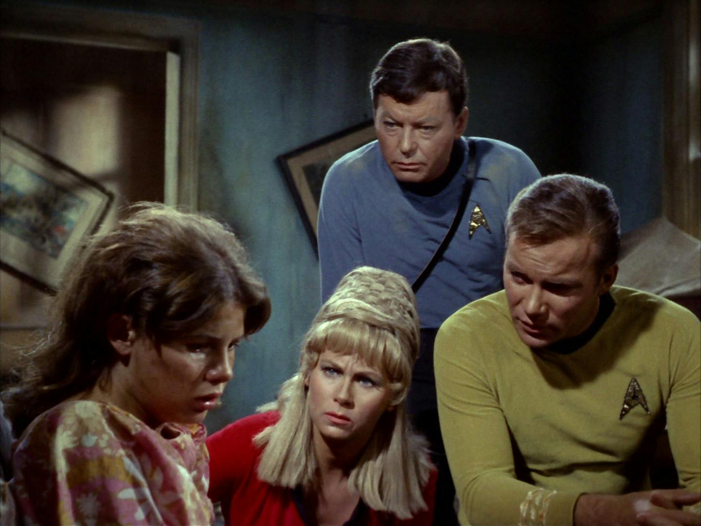 On an Earth-like planet, McCoy, Yeoman Rand, and Kirk huddle near a disheveled teen girl who tells them about how adults on the planet are ravaged by a plague in 'Miri'
