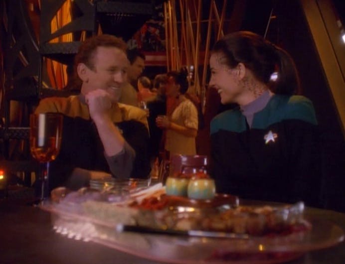 O'Brien and Jadzia Dax grin and laugh after Quark set a plate of Regova eggs at their table in 'Destiny'