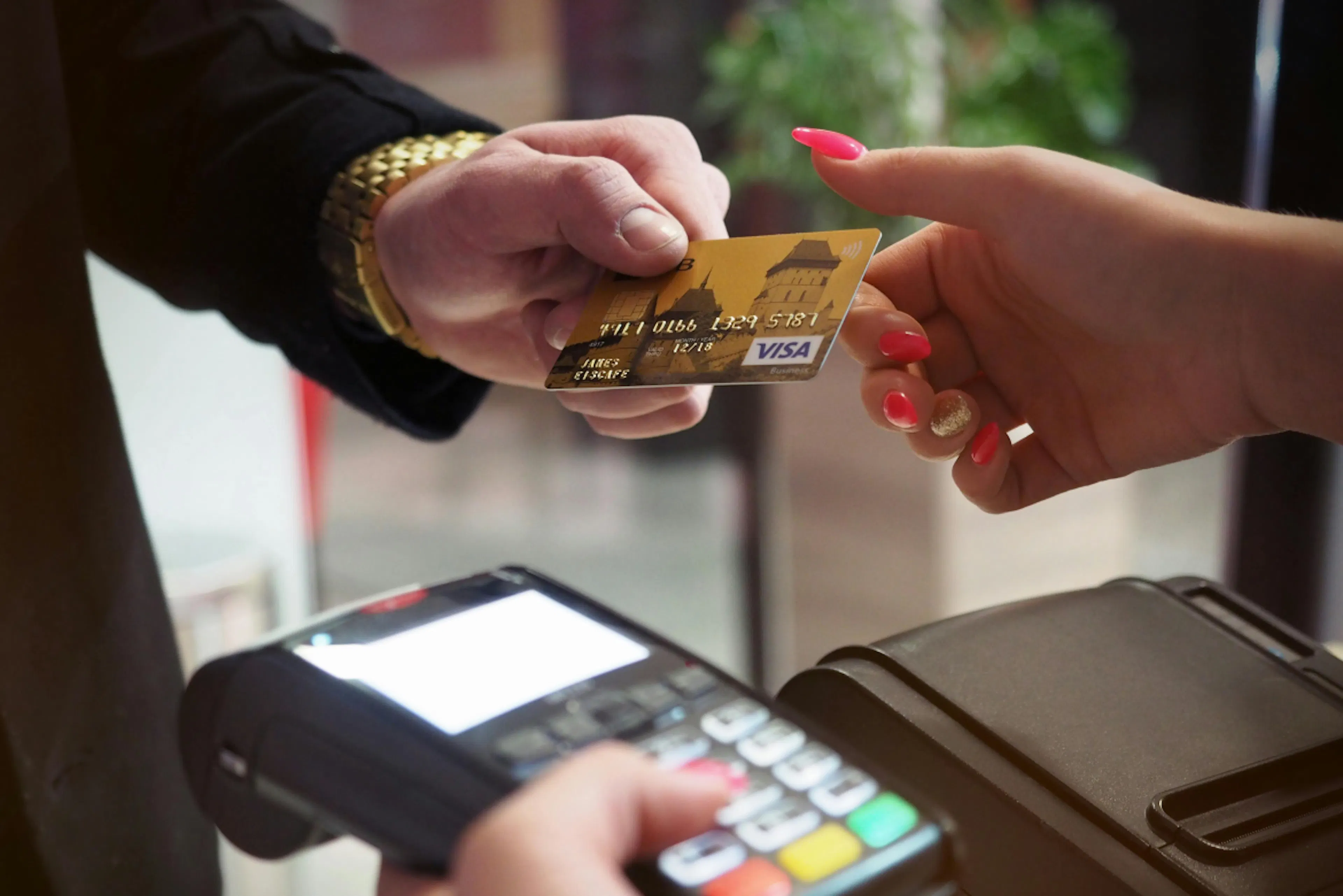 Man handing a credit card to a lady with a POS terminal