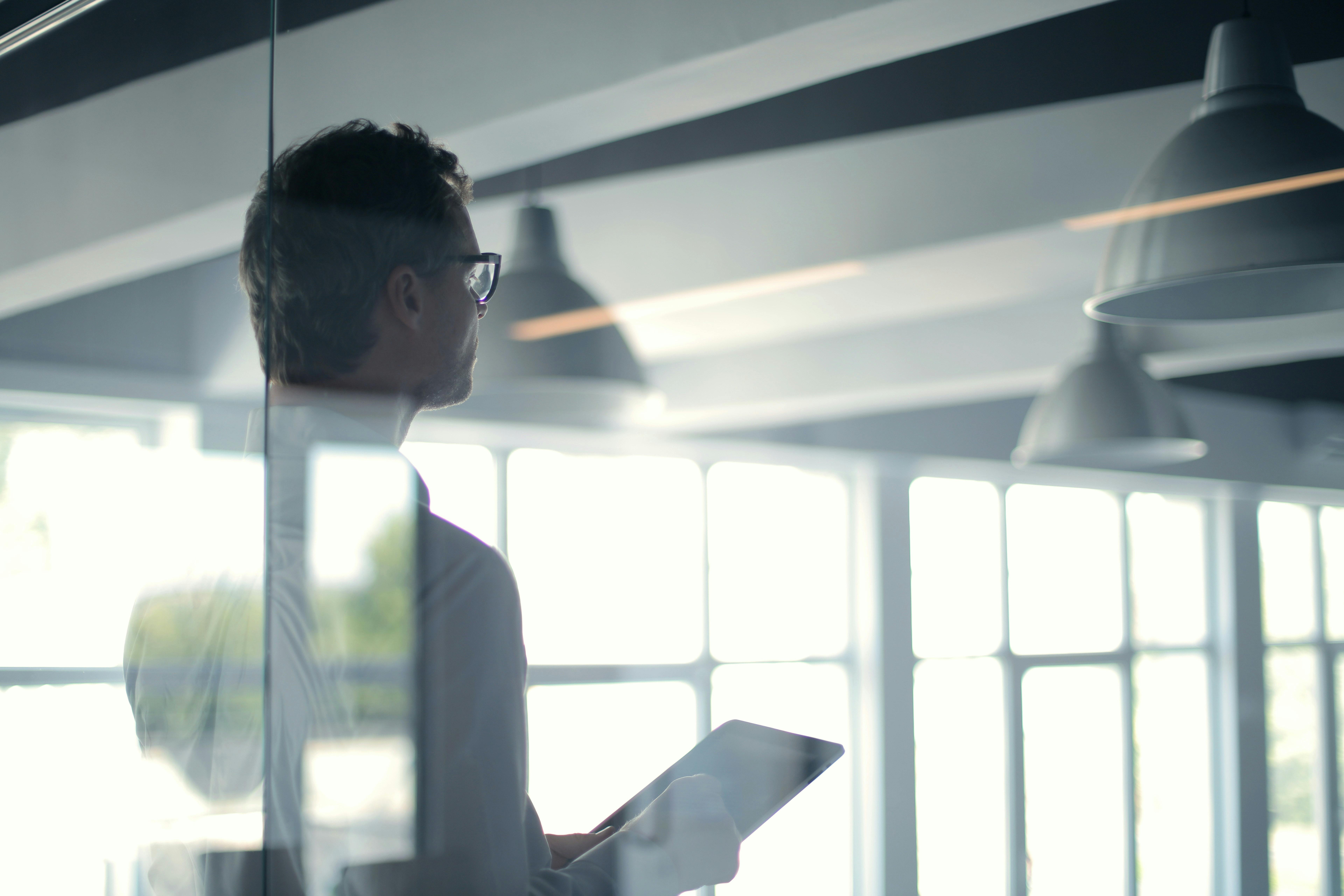 A professional man in an office setting using a tablet to look at a corporate bank account