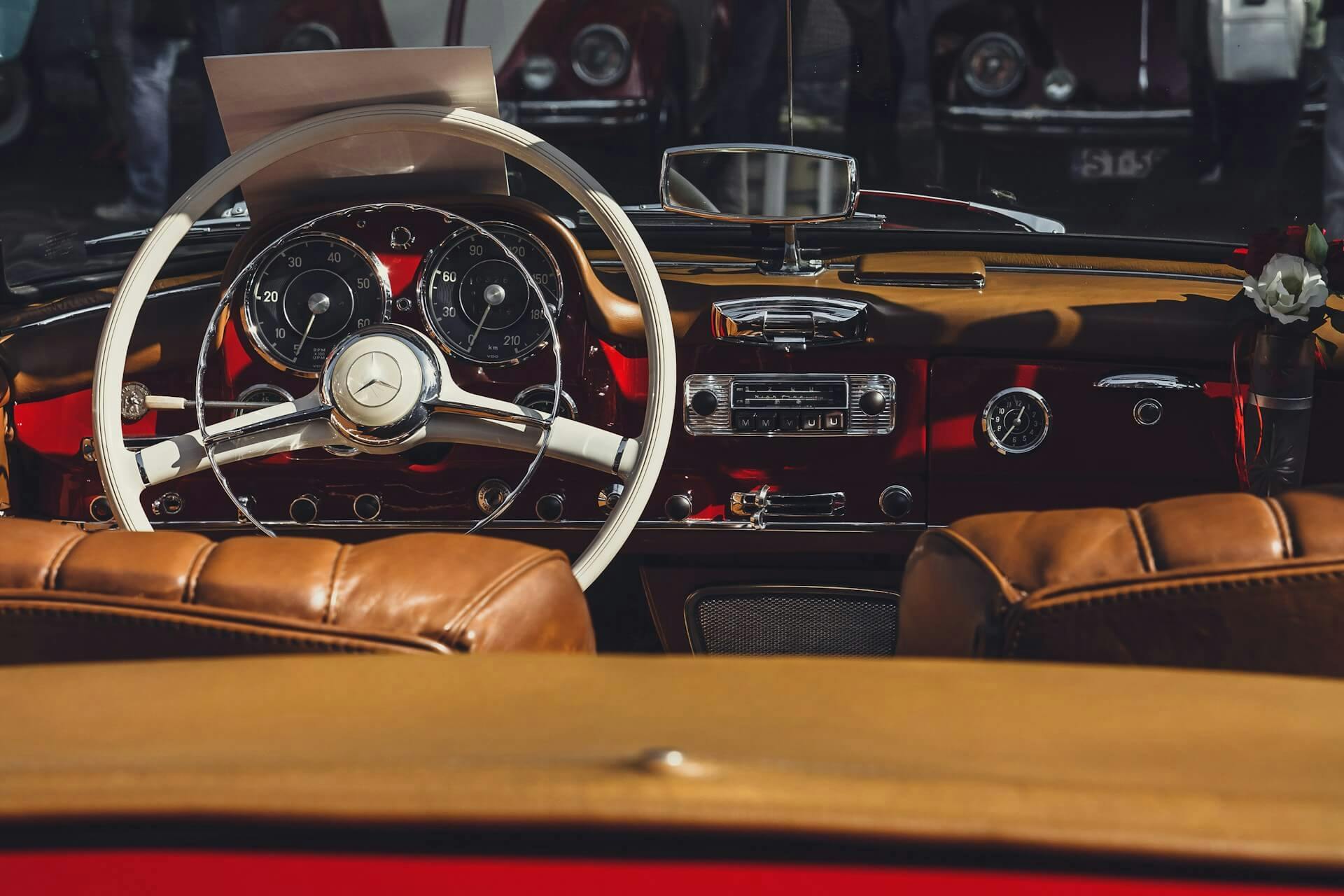 Vintage car interior with leather seats, classic dashboard, and steering wheel.