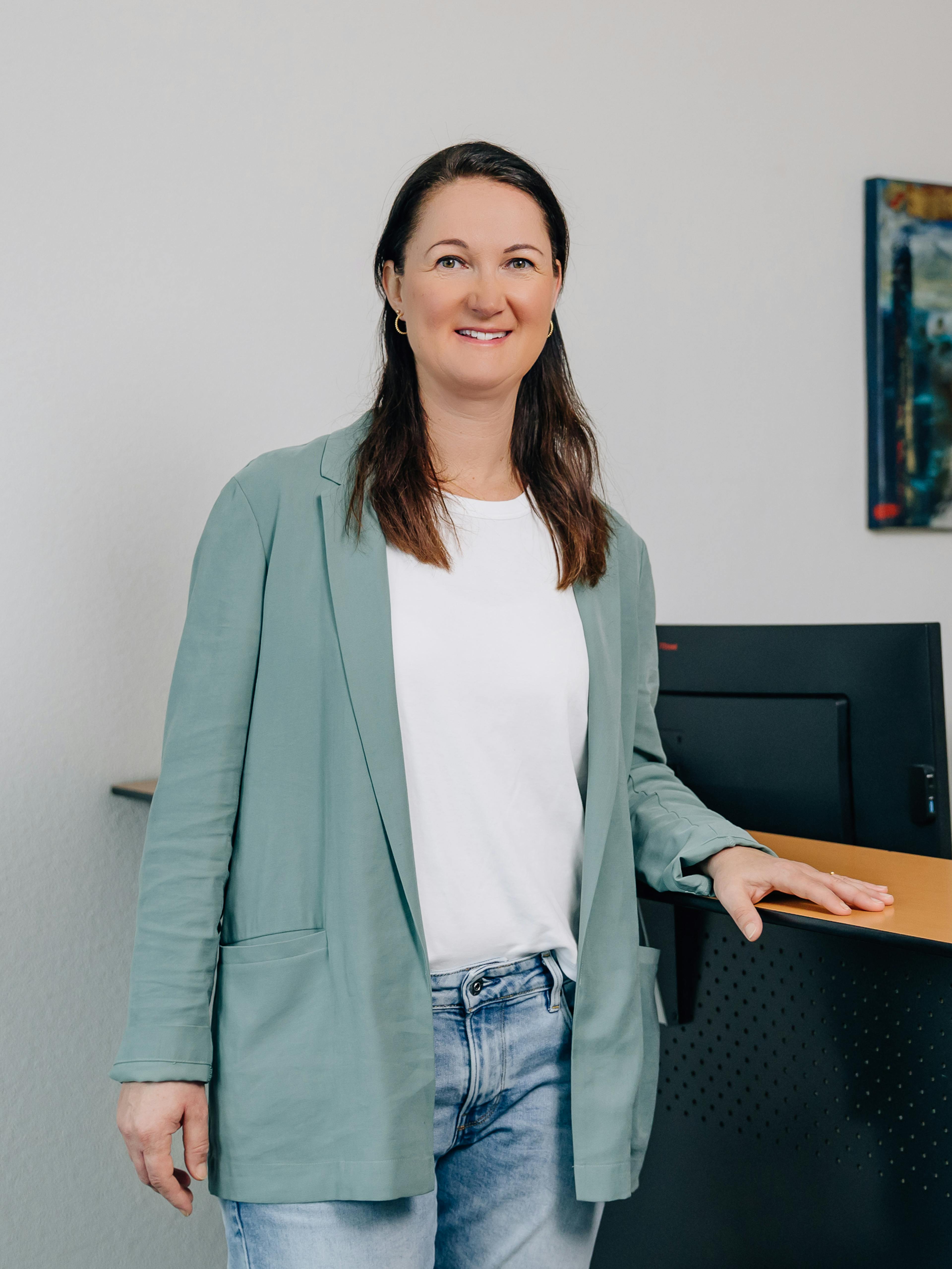 Bild von Michaela vor einem Schreibtisch