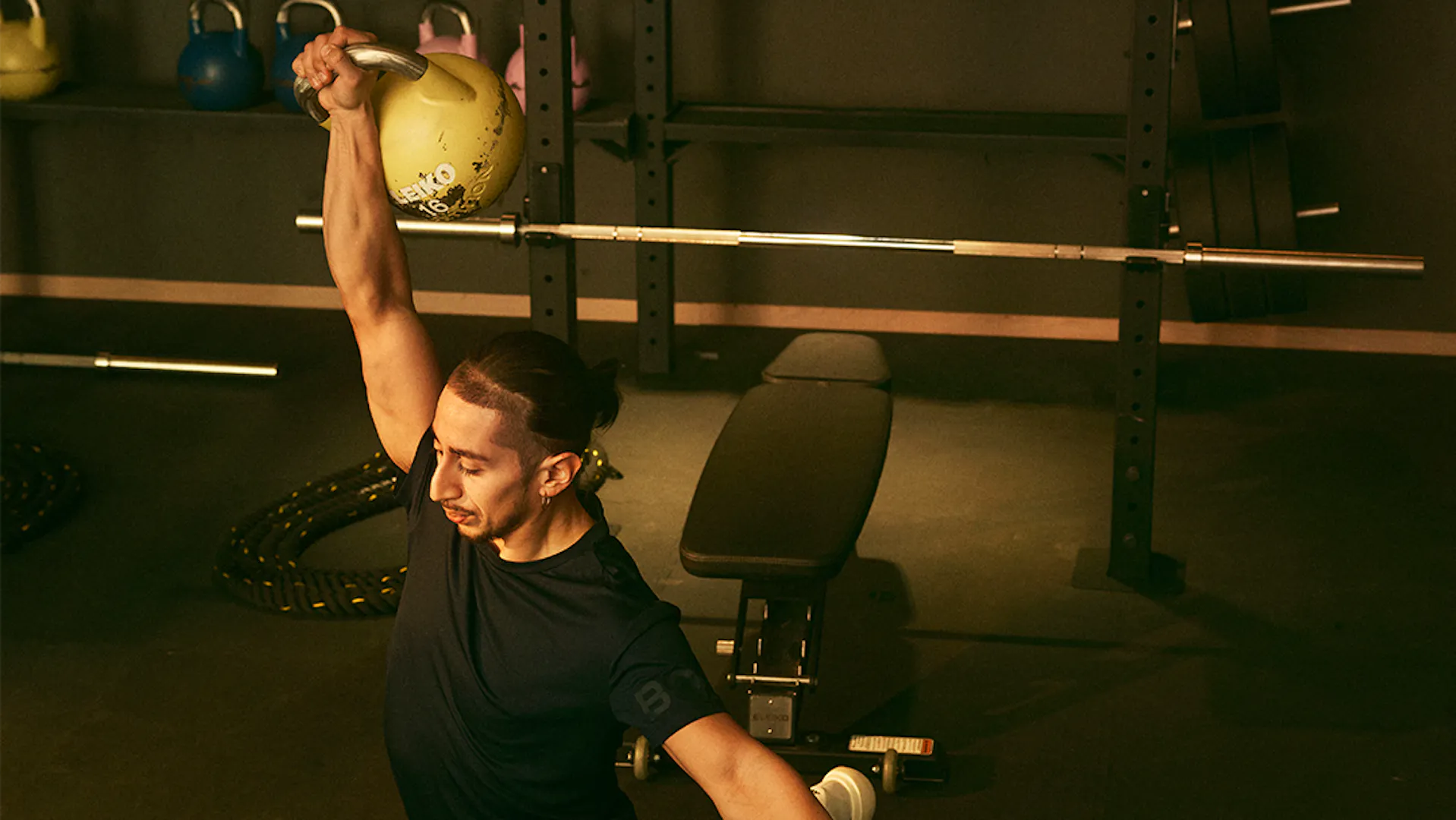 Man gör utfall och håller en hantel ovanför huvudet på STC-gym