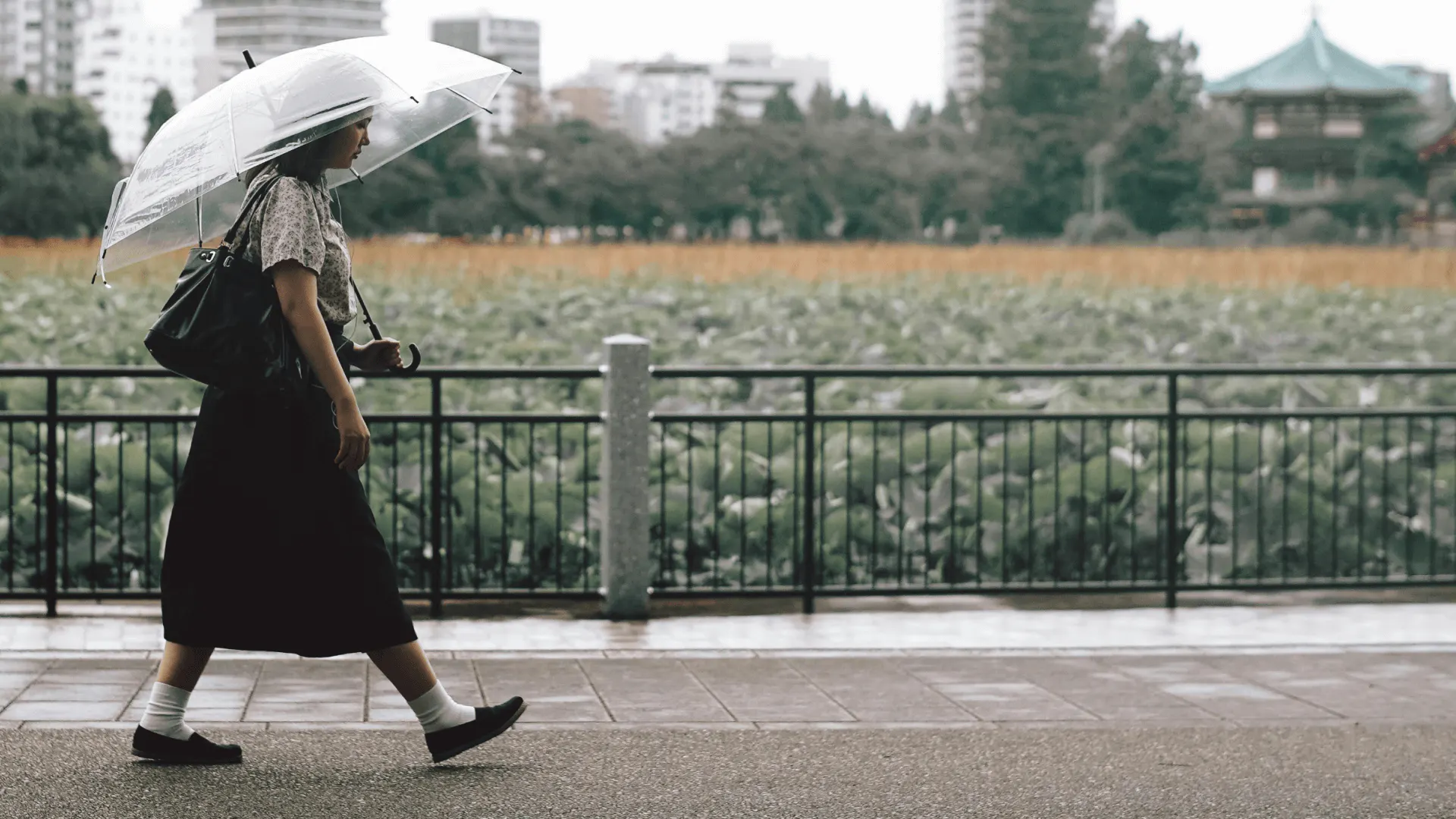 Japansk tjej promenerar i stadsmiljö med paraply