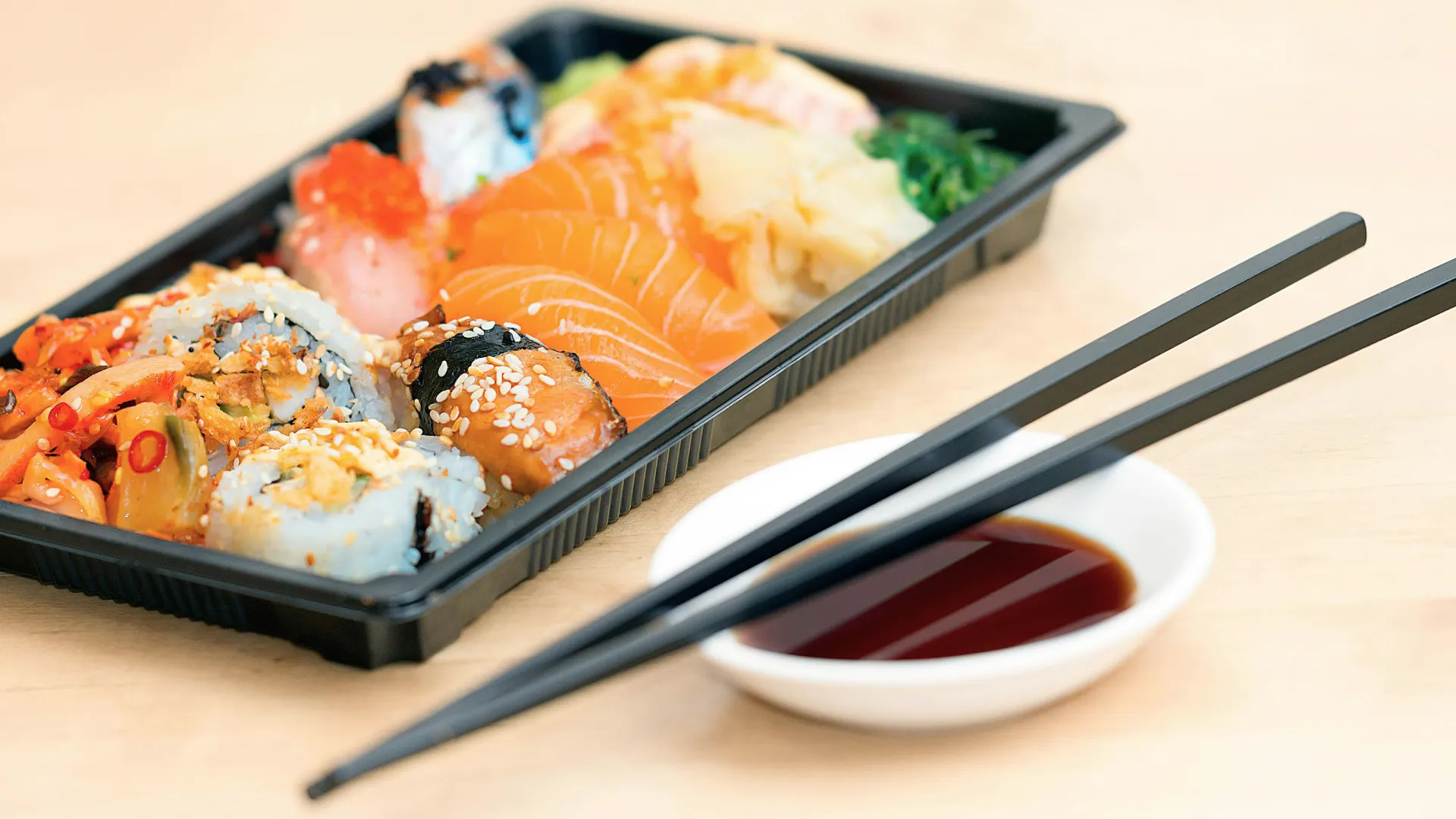Förpackning med olika sorters sushi, en skål med soya och ätpinnar
