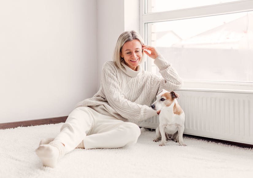 Frau sitzt mit ihrem Hund vor energieeffizienter warmen Heizung von Steinkühler in Leverkusen.