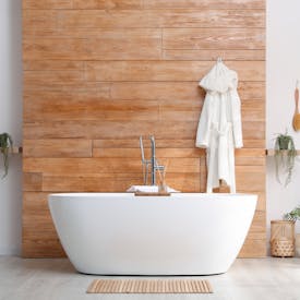 Freistehende Badewanne vor Holzwand als Element der Teilbad Modernisierung von Steinkühler in Leverkusen.