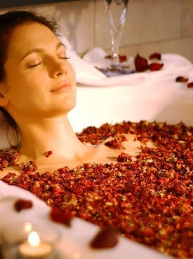 Frau badet mit Rosenblüten in ihrer neuen Badewanne von Steinkühler in Leverkusen