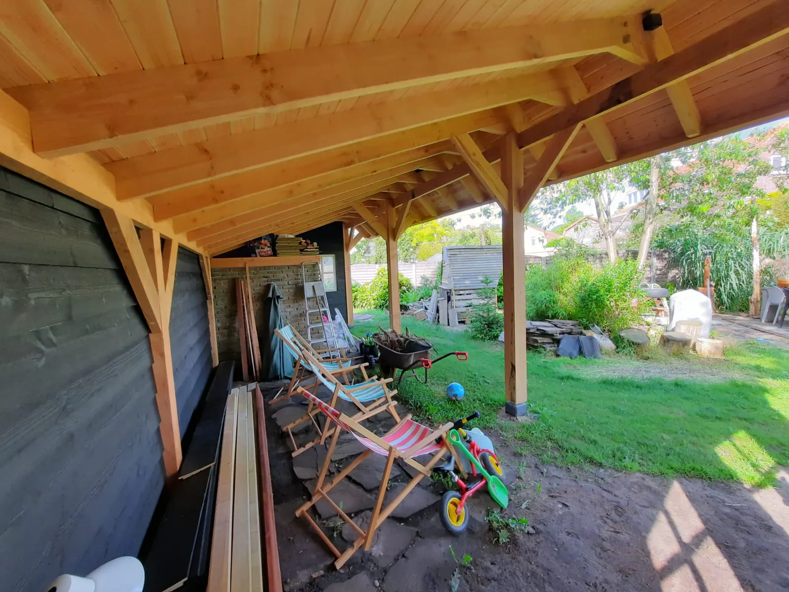 Binnenzijde van veranda met zichtbare houten balken en uitzicht op de tuin