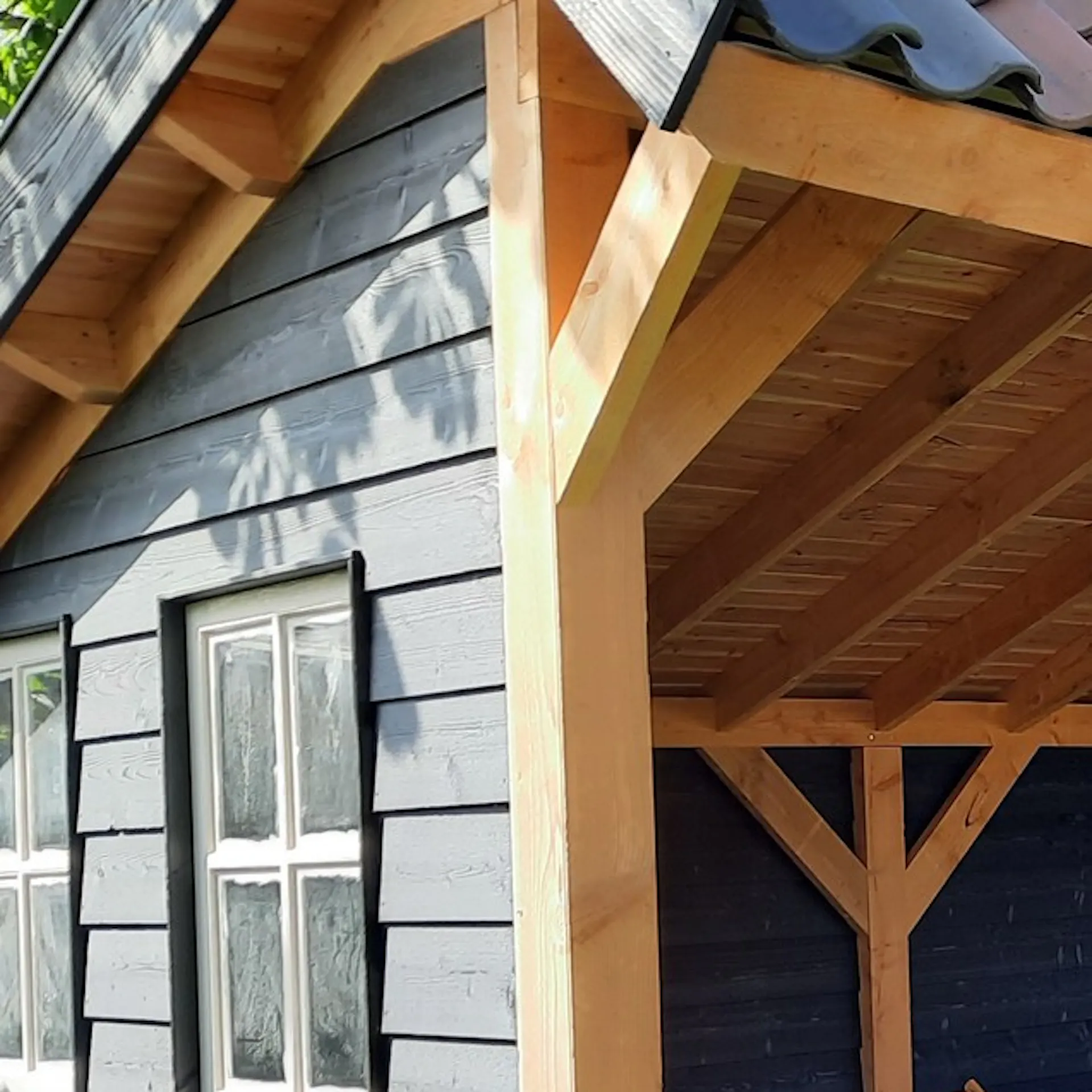 Detail van houten staander, schoren en dakbeschot bij de veranda