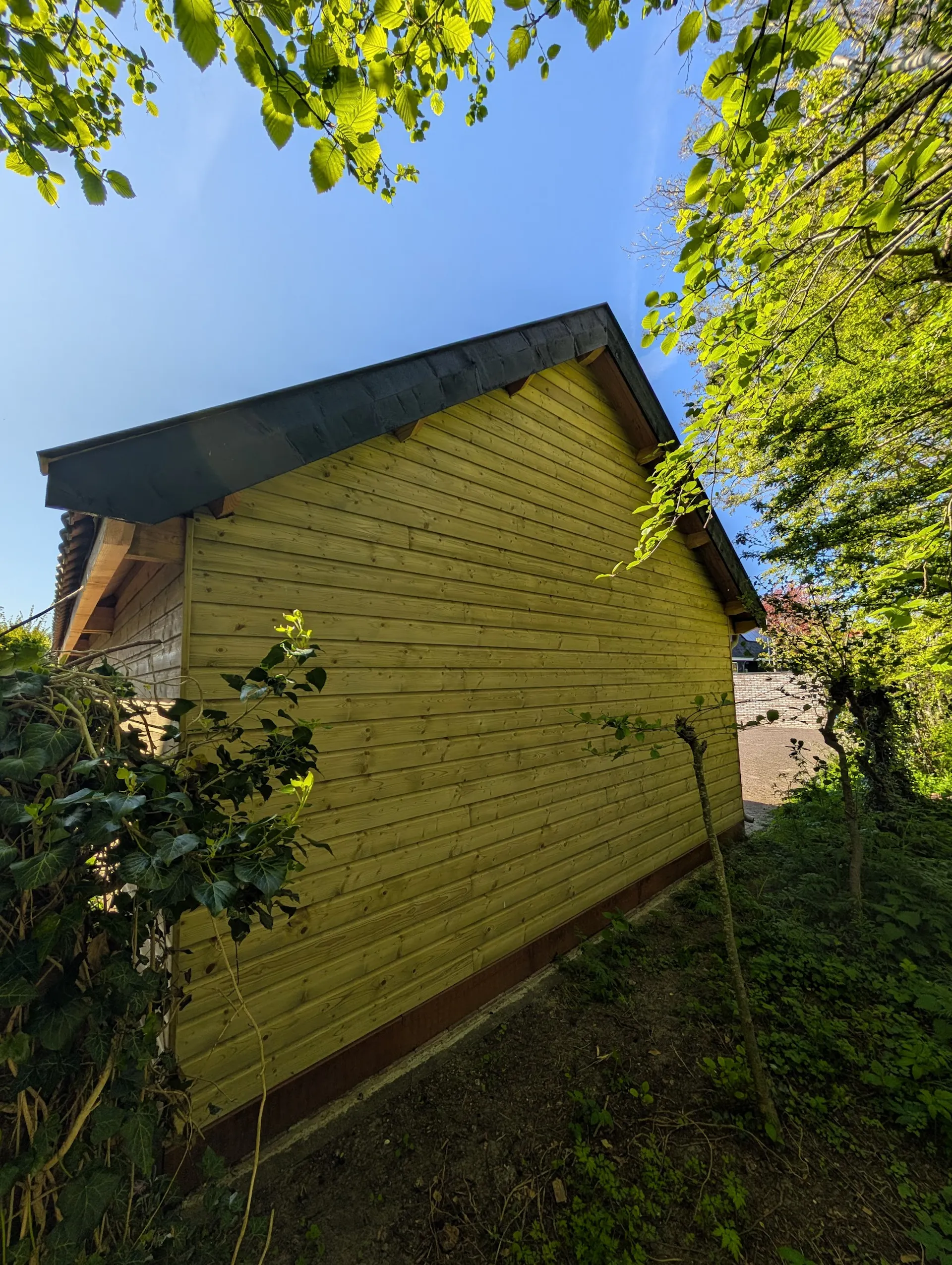 Houten achtergevel van de schuur tussen groene beplanting
