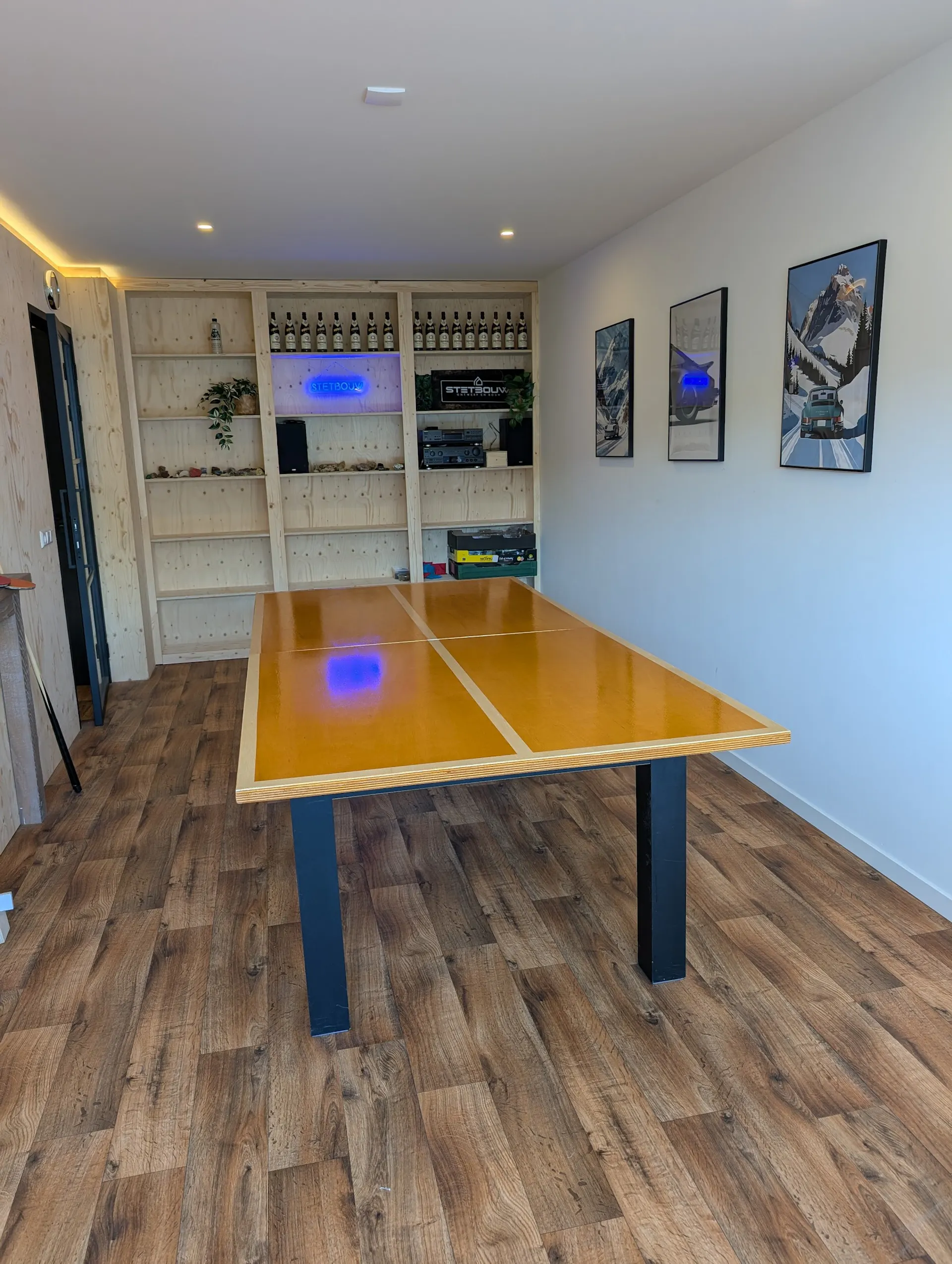 Afgewerkte tafeltennisruimte met houten kastenwand en verlichting