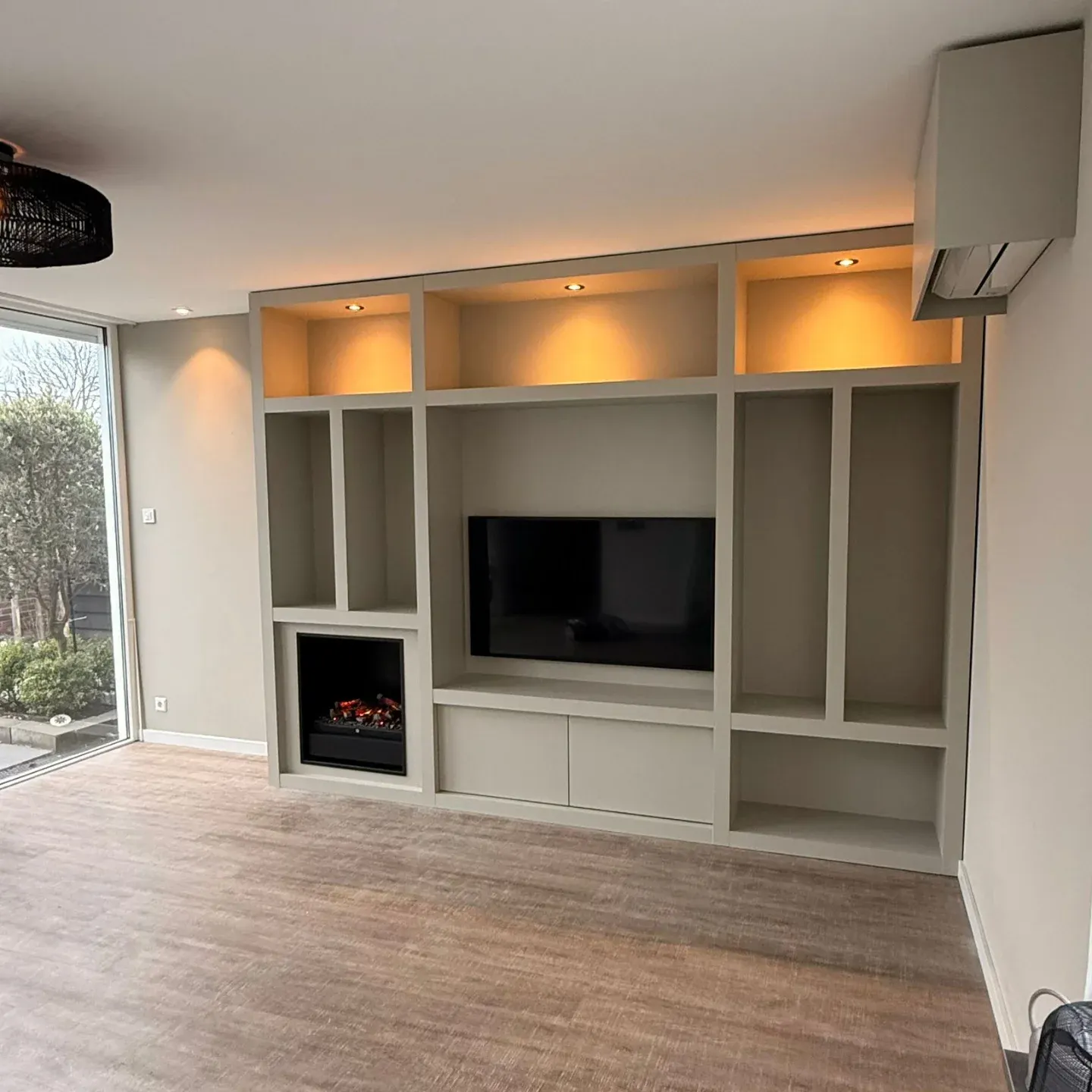 Lege maatwerk cinewall met open vakken, televisie, sfeerhaard en inbouwspots