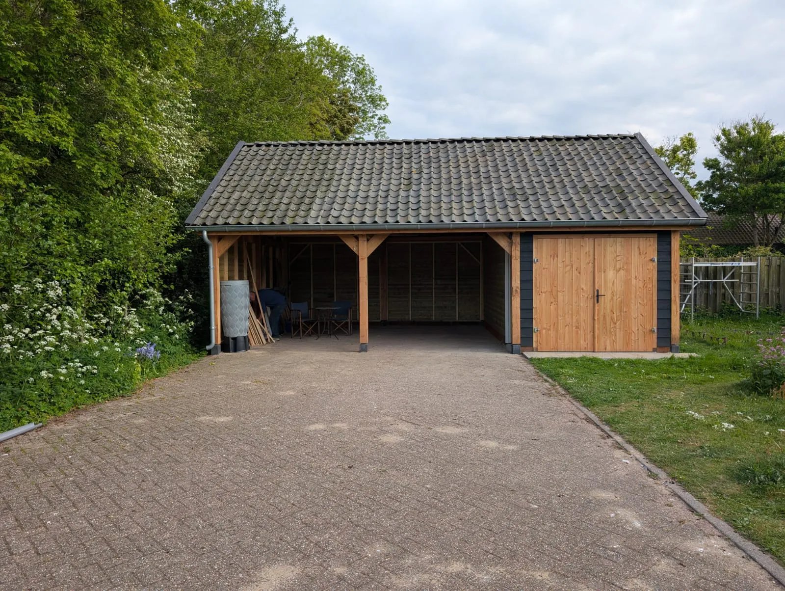 Afgebouwde schuur met open overkapping, houten deuren en pannendak