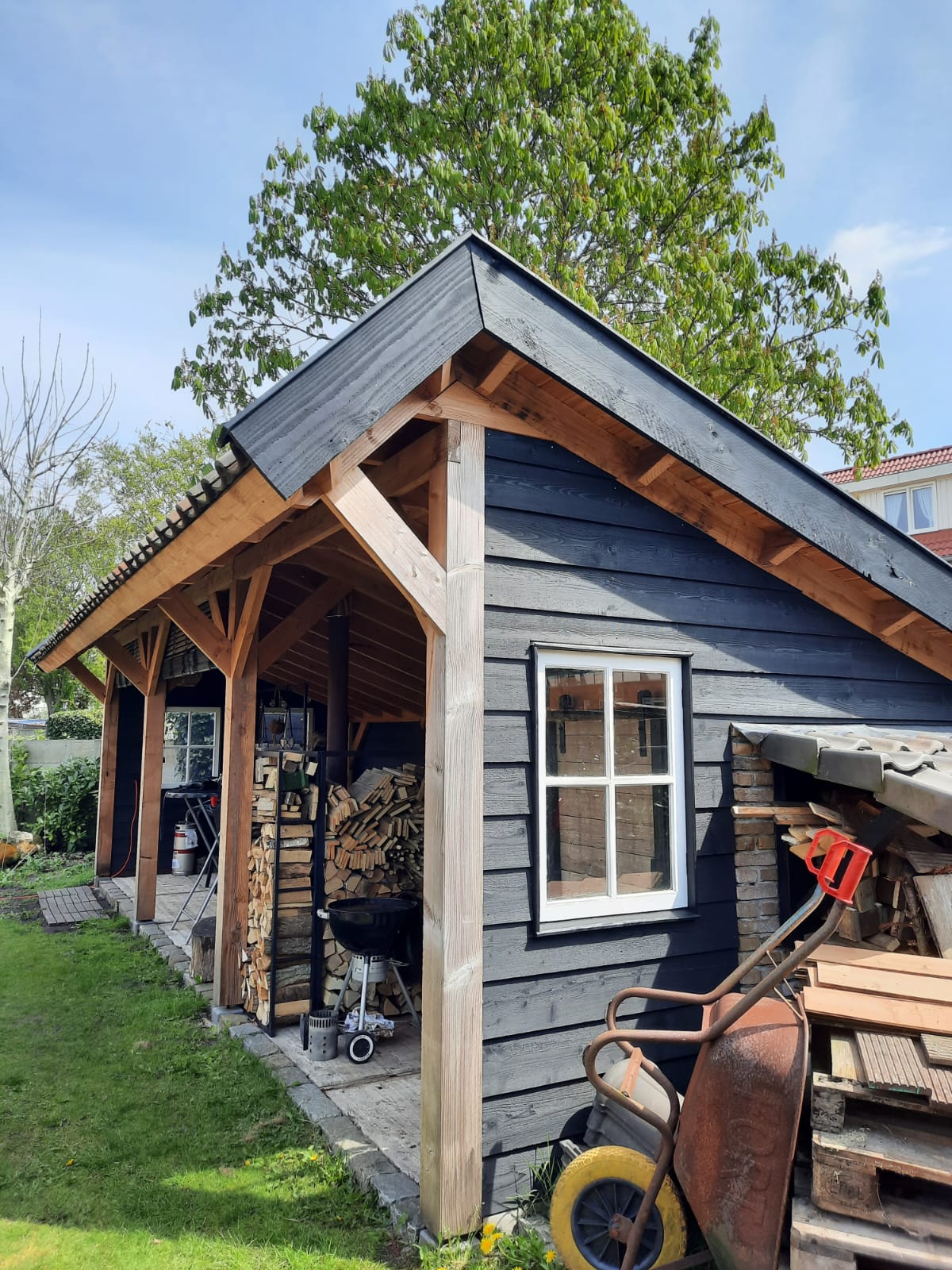 Zijaanzicht van houten veranda aan bestaande schuur in de tuin