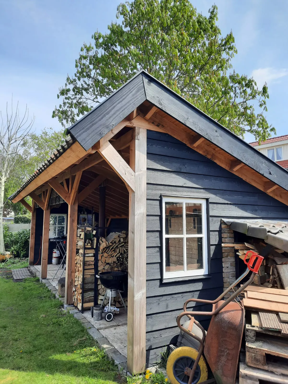 Zijaanzicht van houten veranda met zadeldak en zwarte gevelbekleding