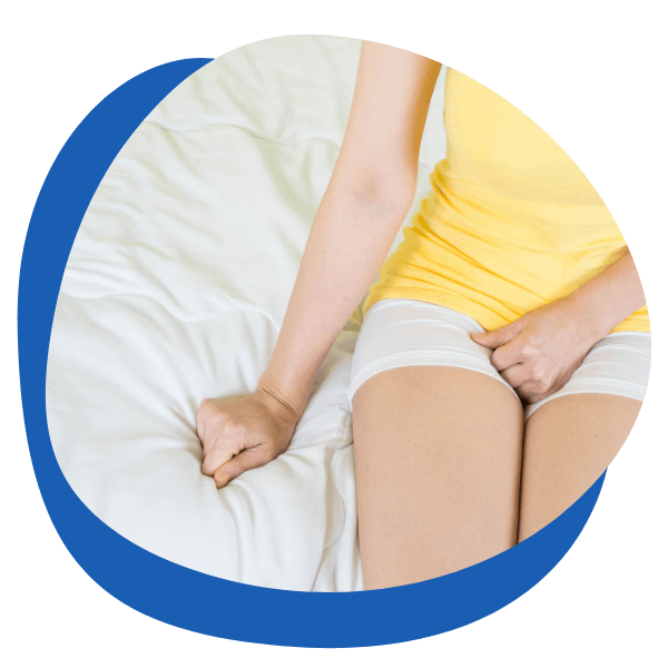 a dressed young woman sitting on her bed and having her hand on her itchy vagina due to thrush - round icon for women's vaginal candida thrush treatment category from My Private Pharmacist Online pharmacy