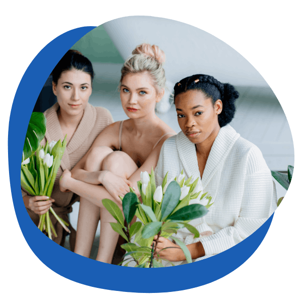 three beautiful woman of different races sitting together holding white flowers - round icon for skincare category from My Private Pharmacist Online pharmacy