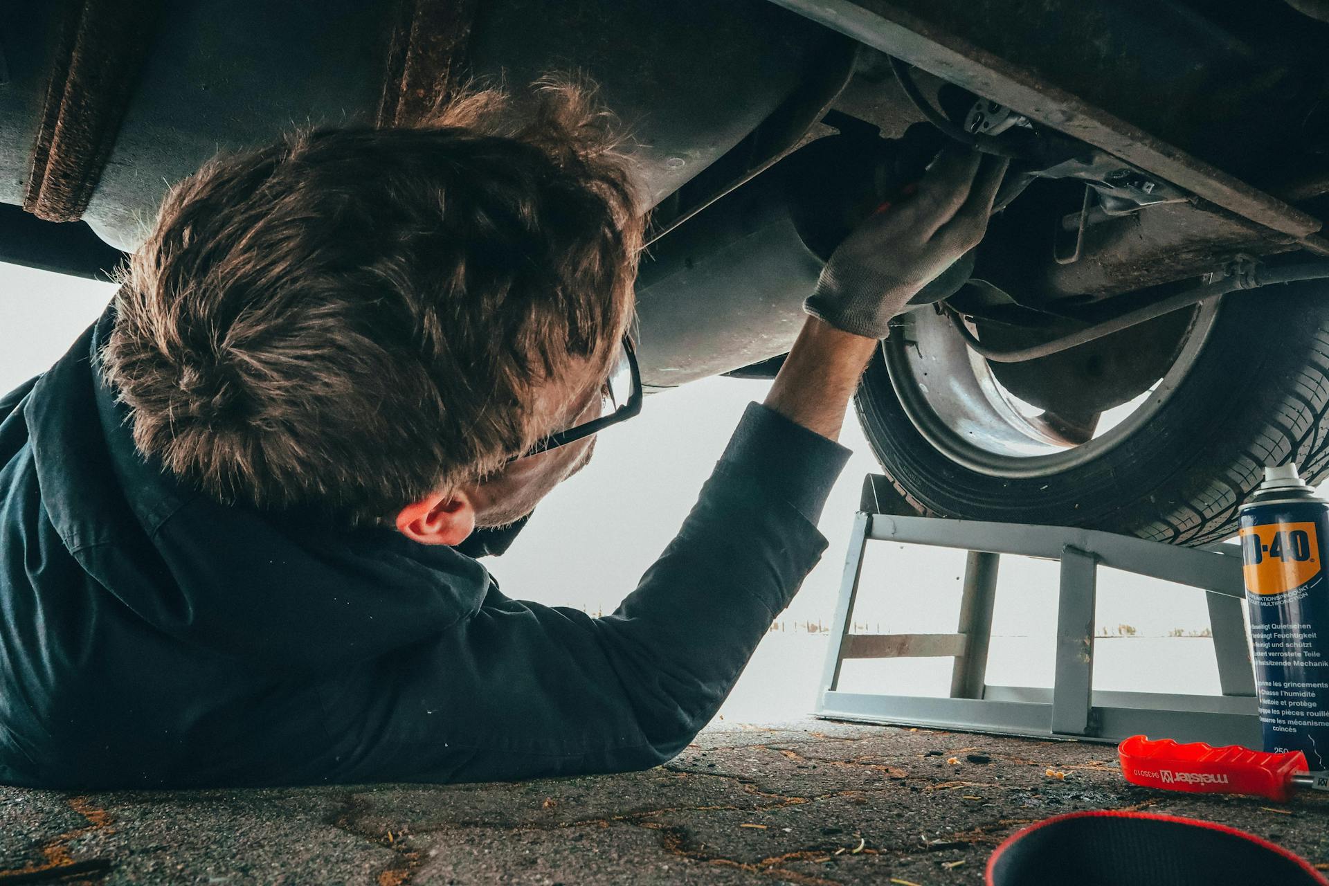 a man applying WD-40 to the bottom of his car