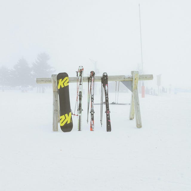 skis and a snowboard against a stand in the snow