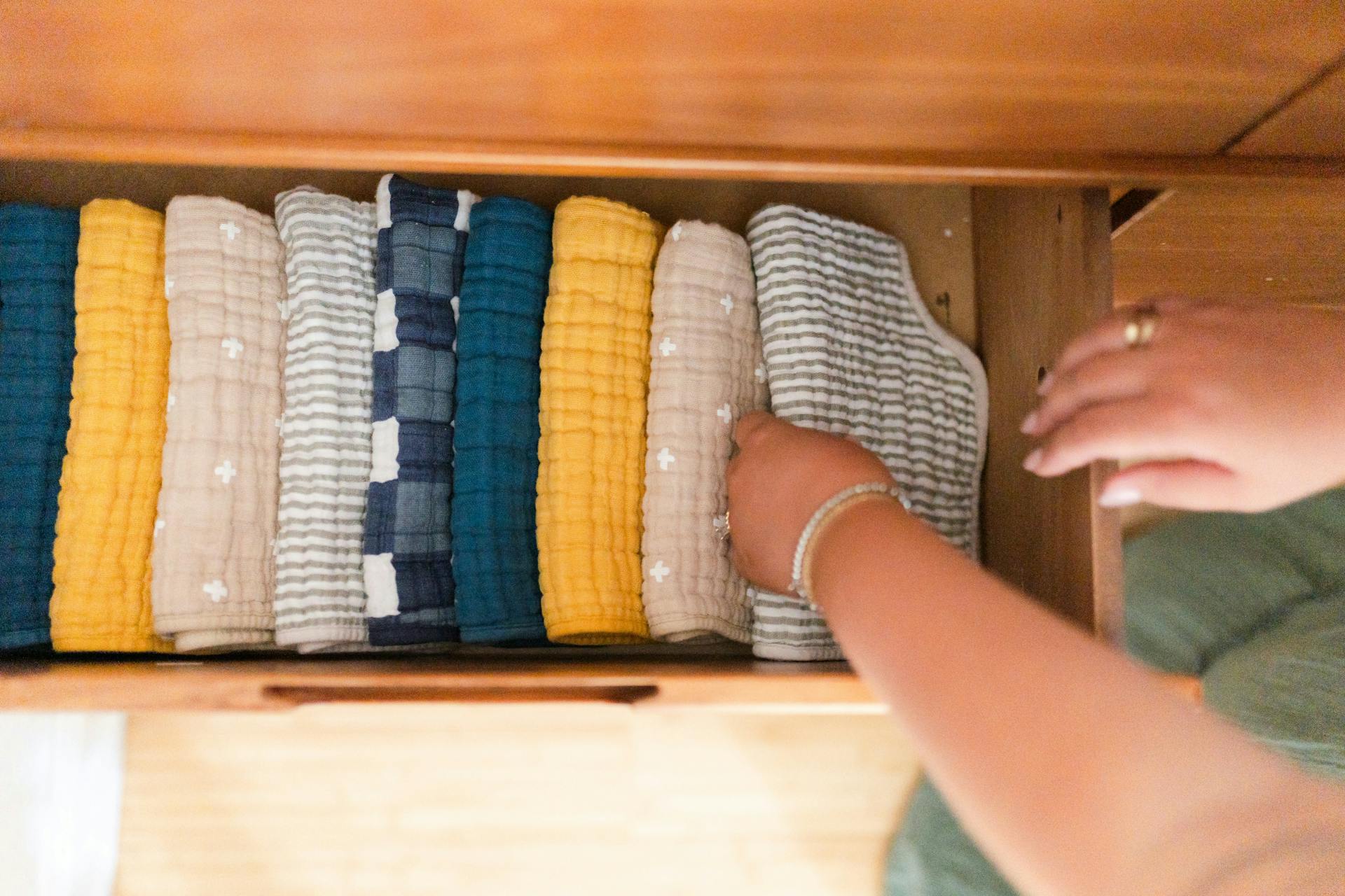 a woman sorting through a box of baby clothes in storage