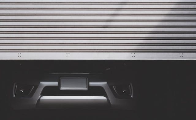 A car being stored in a garage with the door half down 