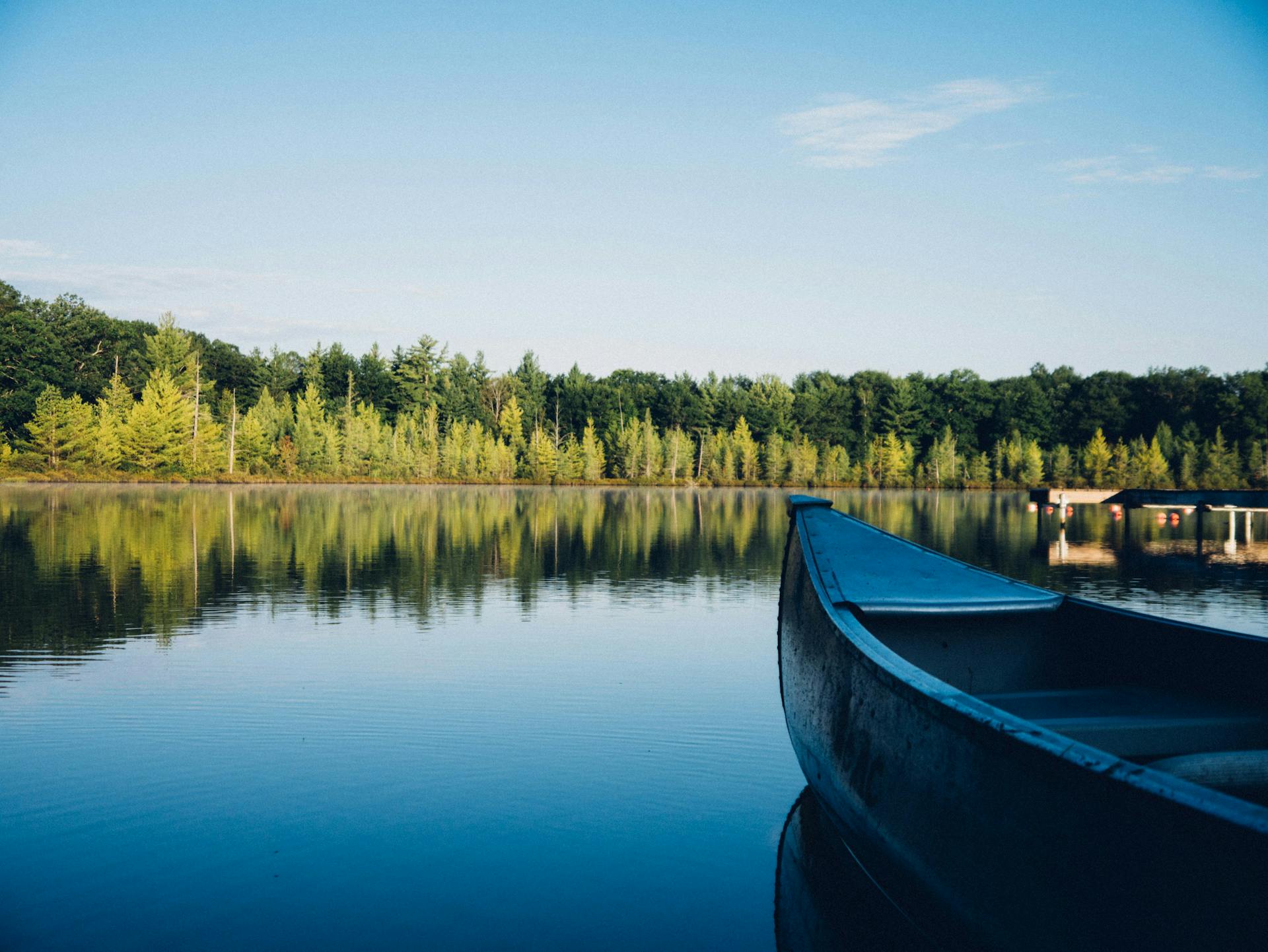 canoe sitting on a lake with a dock next to it