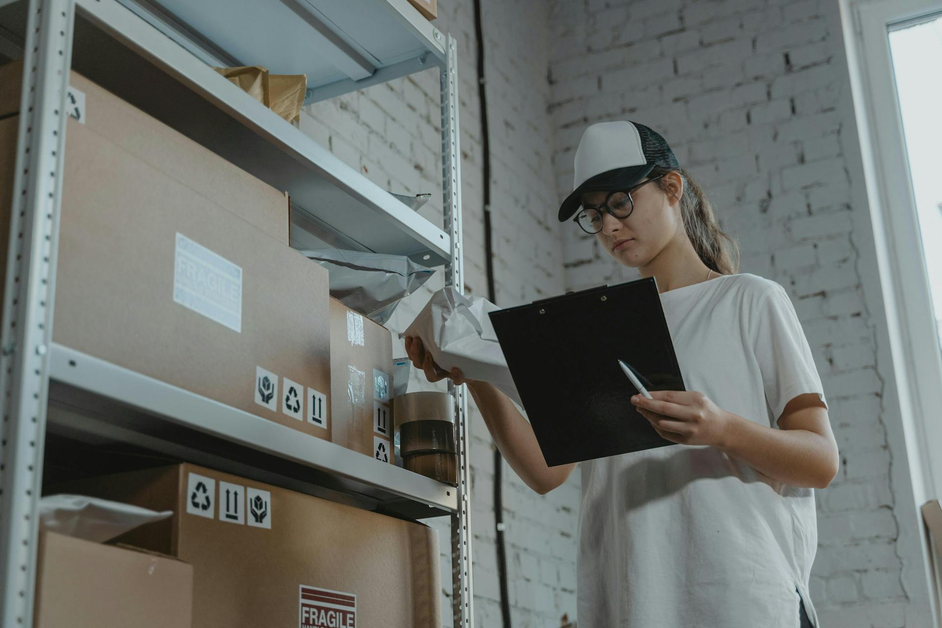 a woman holding a clipboard labeling storage boxes 