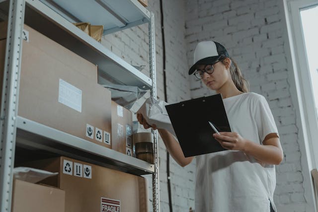 a woman holding a clipboard labeling storage boxes 