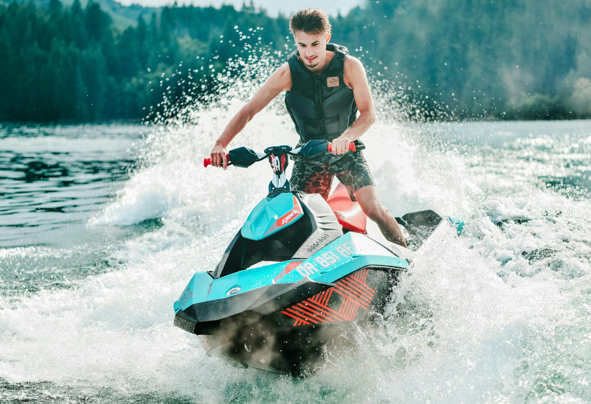 A man riding a jet ski over a wave on a lake