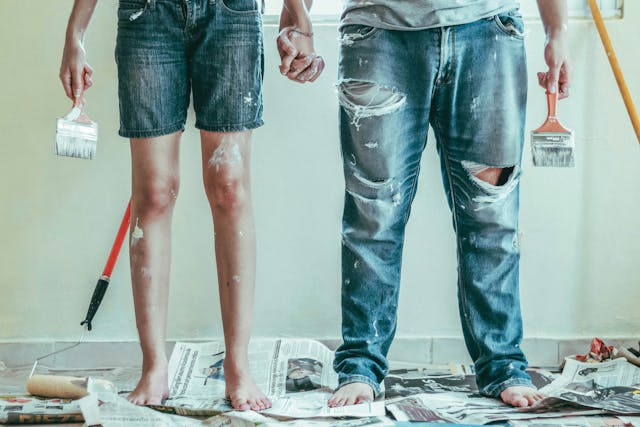 a photo of a man and a woman covered in paint and dirt standing in the middle of a DIY home repair project 