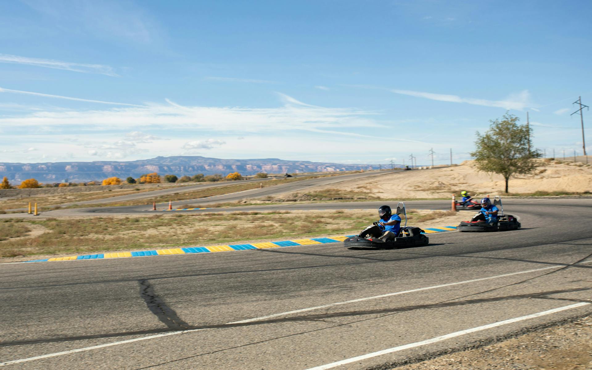 People racing go-karts on a race track with mountains in the background