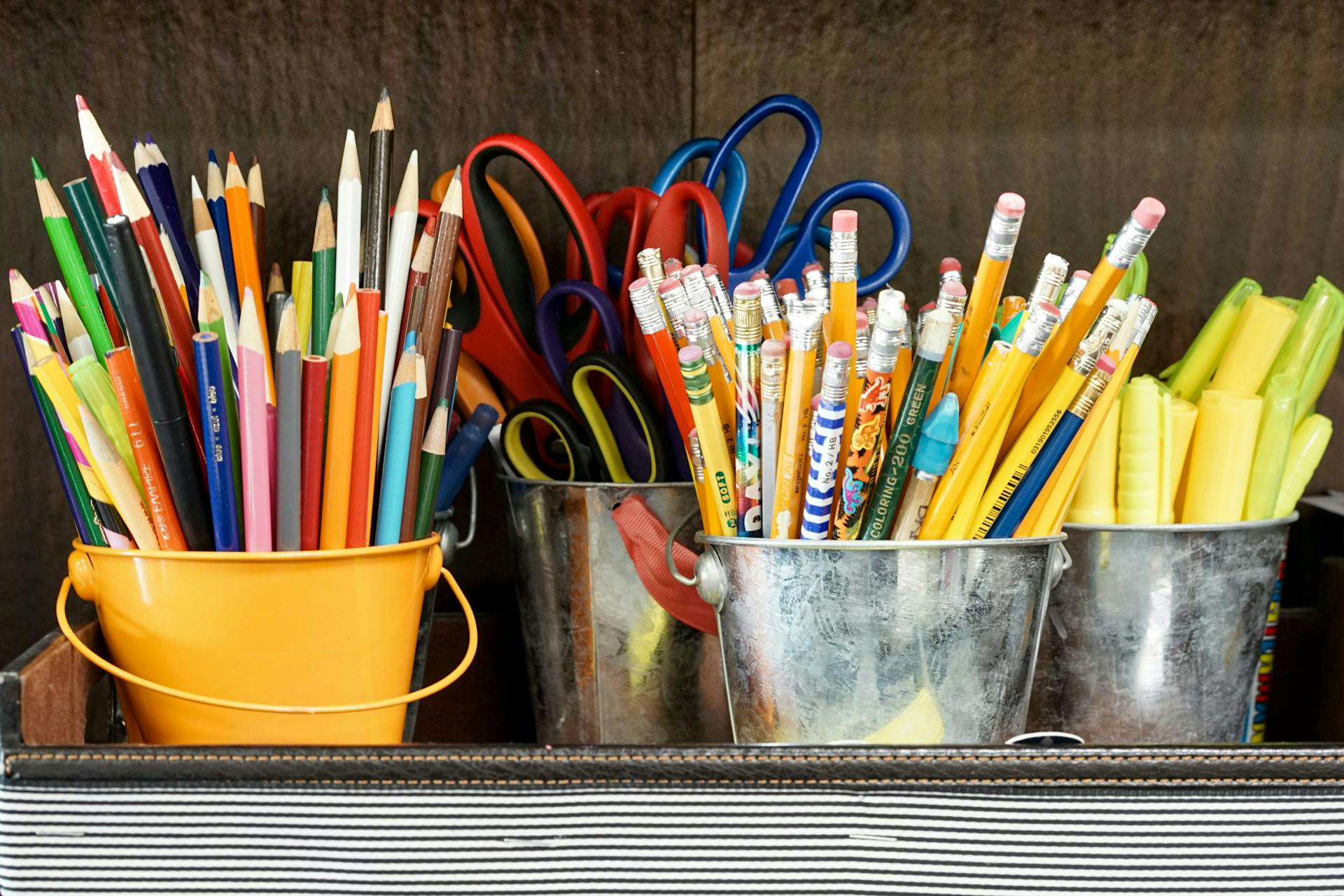 Various pencils, scissors, and other school supplies organized into several small buckets