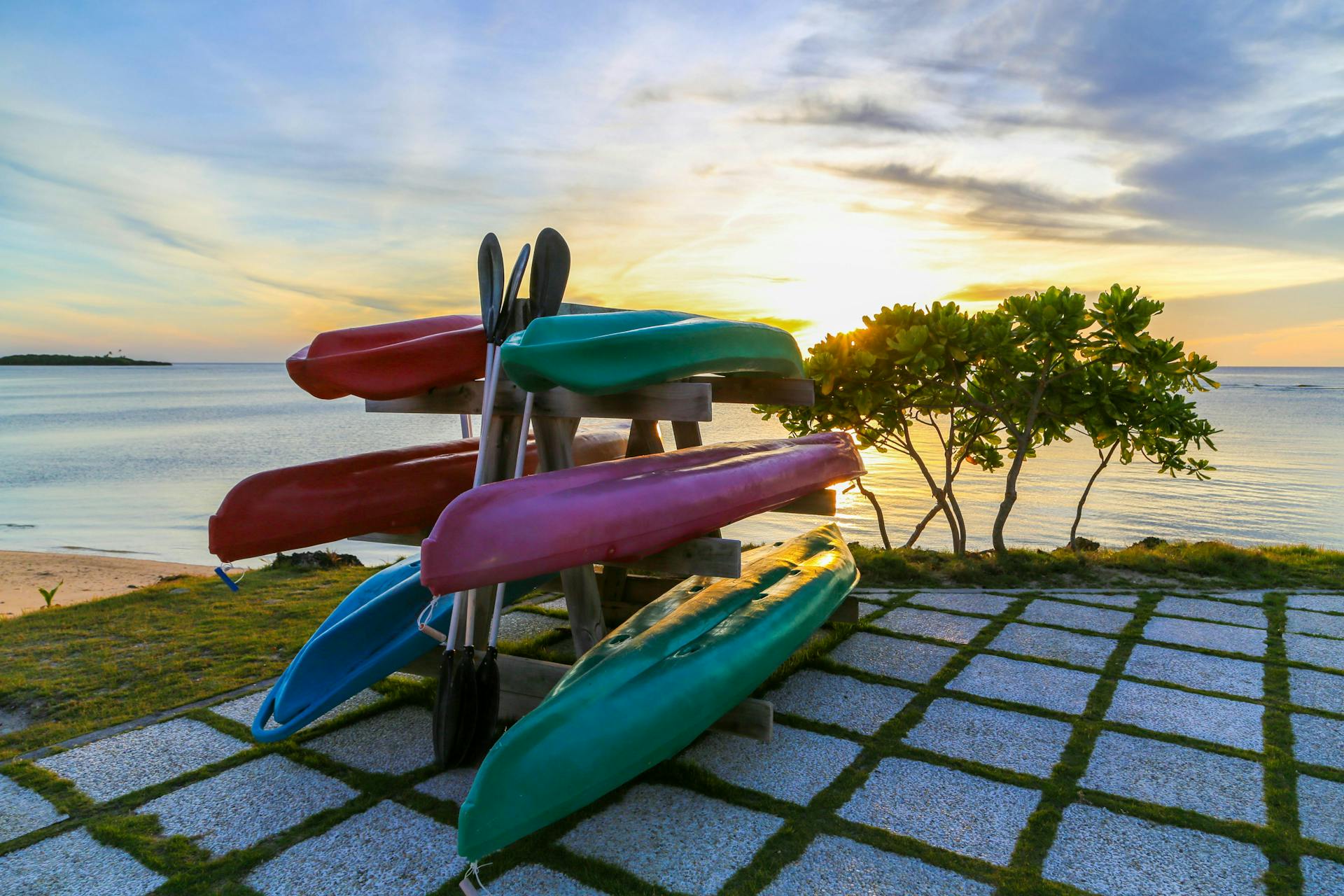 Kayaks on a storage rack next to a beach.