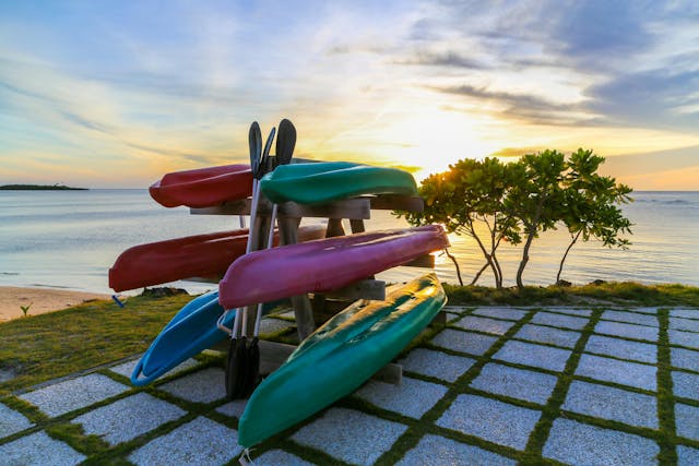 Kayaks on a storage rack next to a beach.