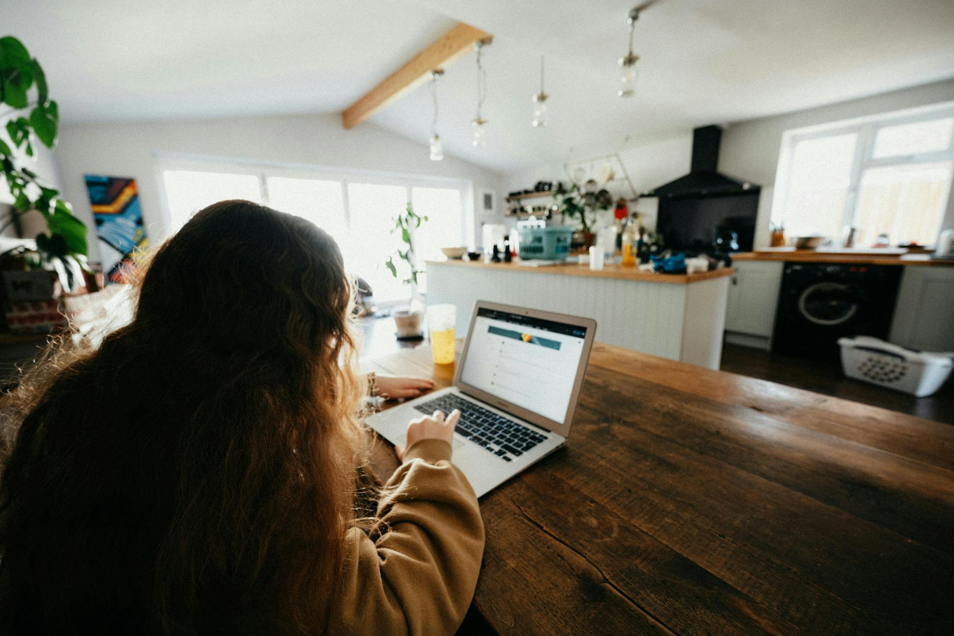 A young girl working on a laptop at the kitchen table